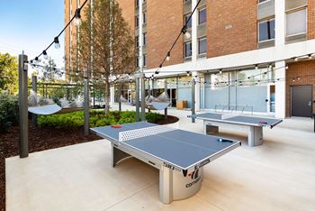 Two ping pong tables in front of a brick building